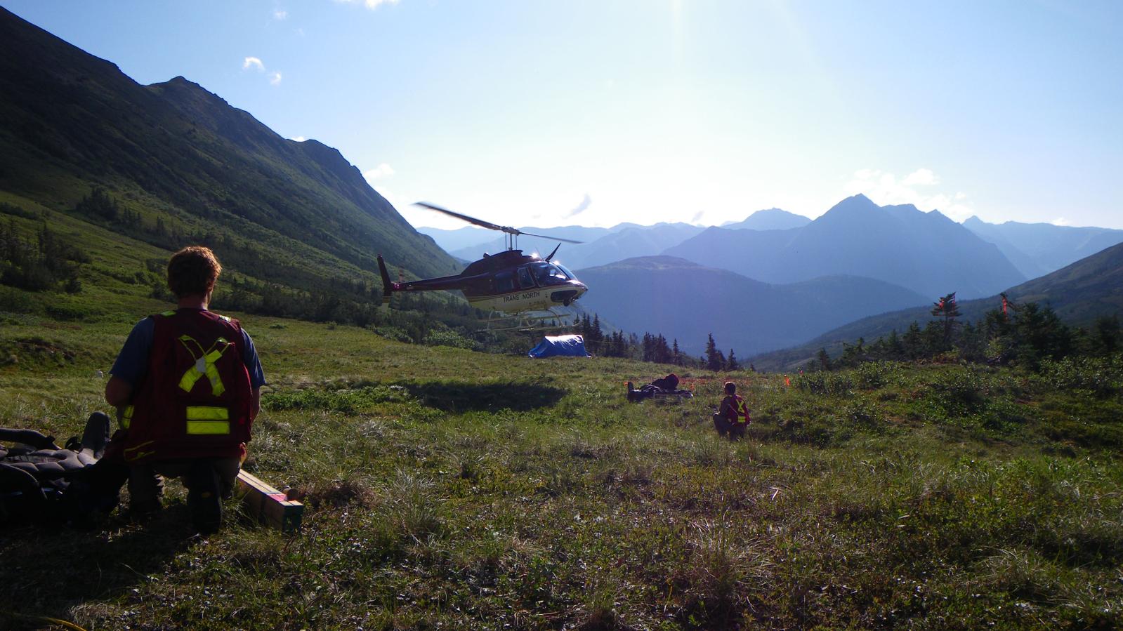 Helicopter dropping of exploration crew Exploration crew drop off in mountain valley with helicopter in background