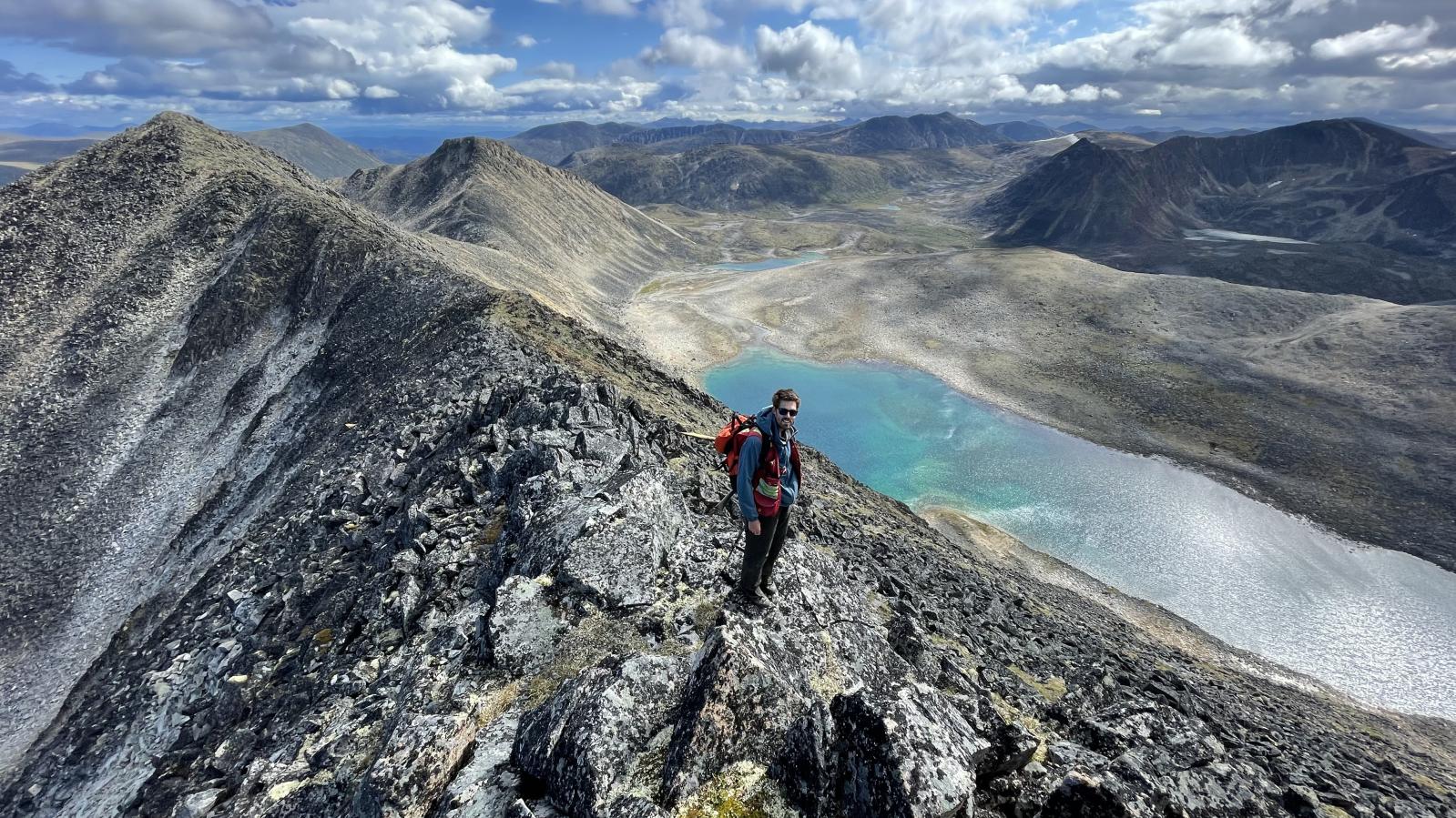 Geologist overlooking a mountain lake from a ridge top at the Findlay property