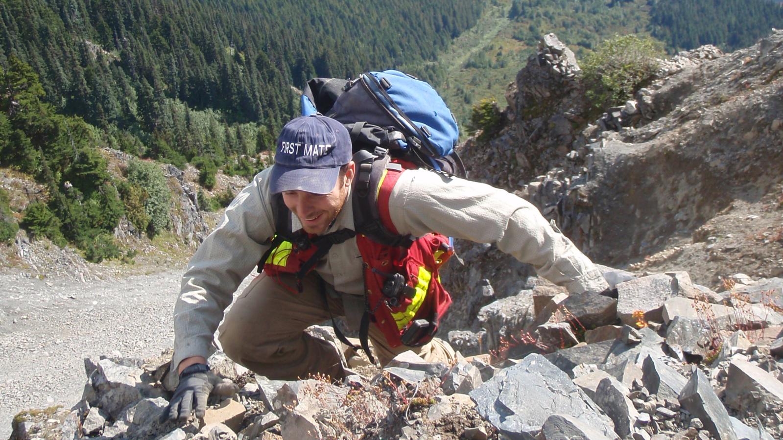 Exploration crew member climbing a very steep slope in NW BC Exploration crew member climbing a very steep slope in northwest BC