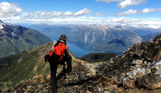 A person with a red backpack on top of a mountain