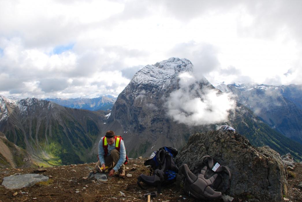 Sampling at Waterloo Showing with Helmut Peak in background - Ice River Complex Project