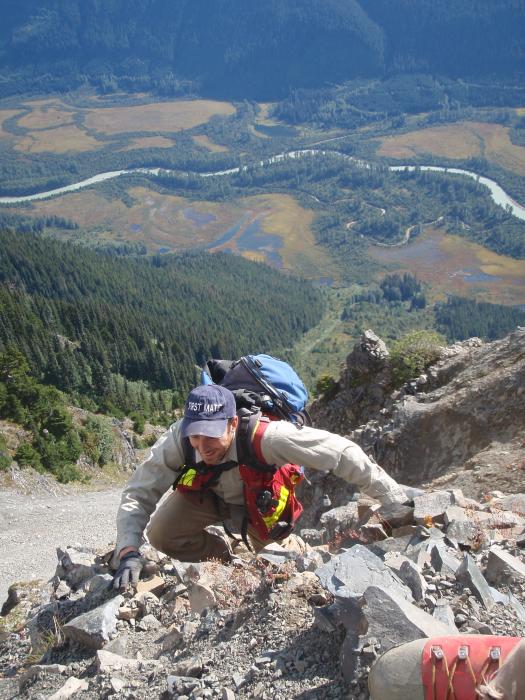 Exploration crew member climbing a very steep slope in NW BC Exploration crew member climbing a very steep slope in northwest BC