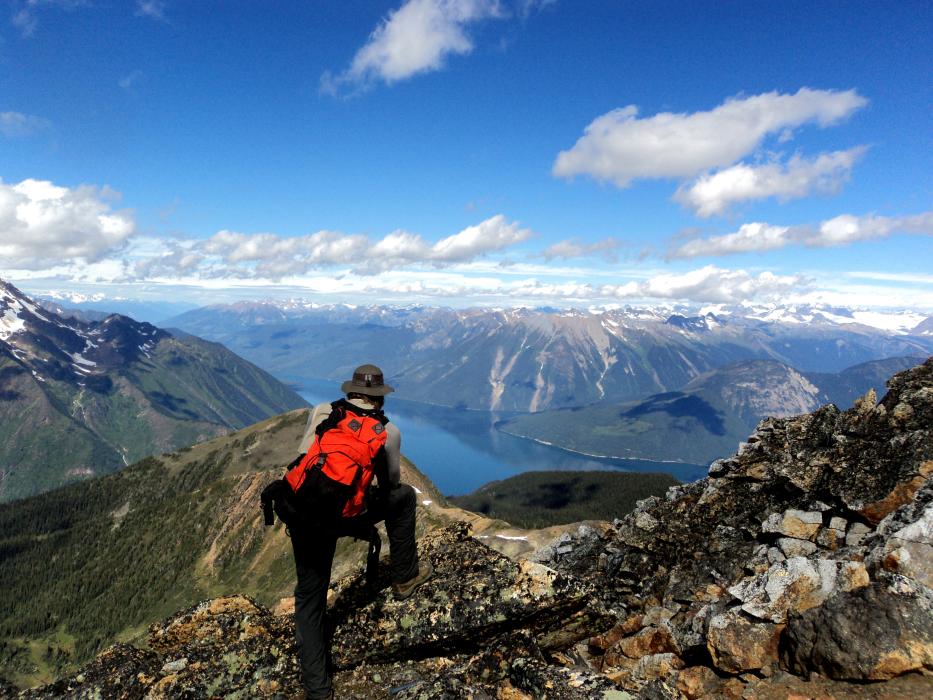 Geologist overlooking a large lake from up in the peaks A geologist among the mountain tops overlooking a large lake